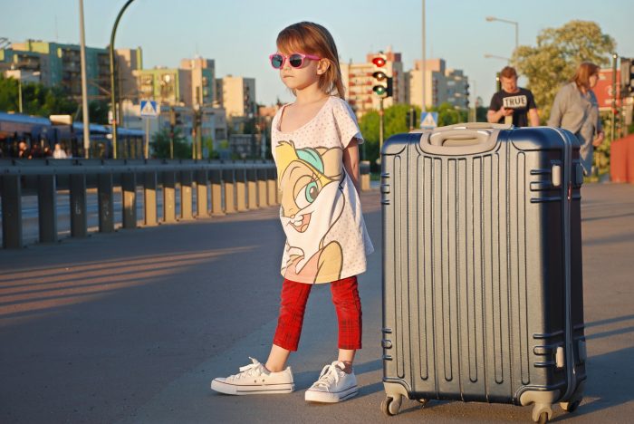 dziewczynka stoi z walizką na ulicy rodzinne wakacje