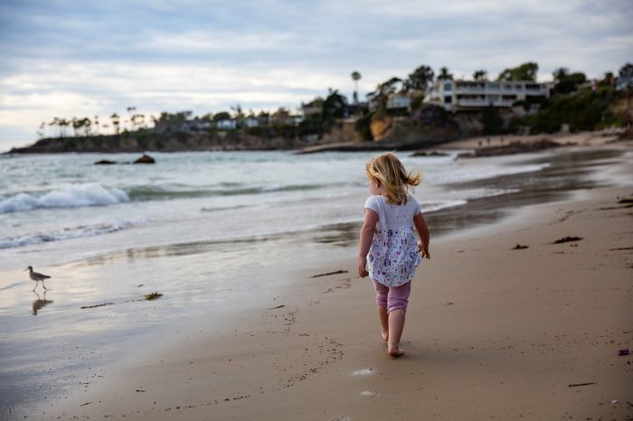 dziecko-spaceruje-po-plaży-w-czasie-wypoczynku-z-rodzicami