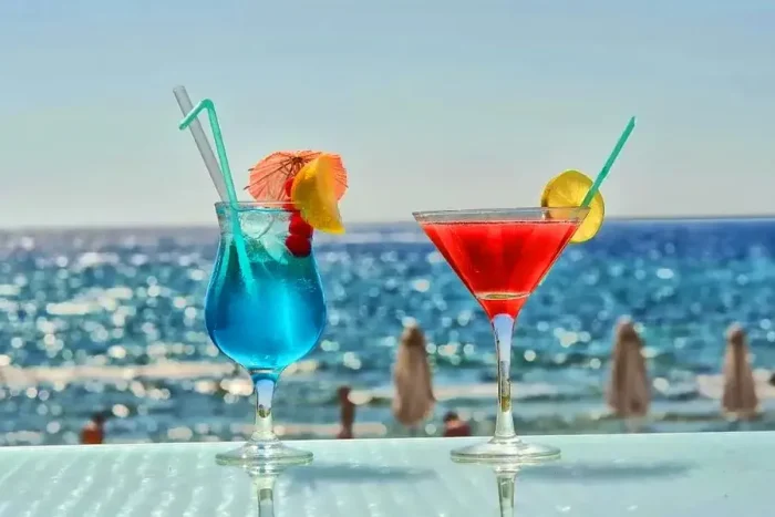 drinki kolorowe z palemkami w tle widoku na plażę 