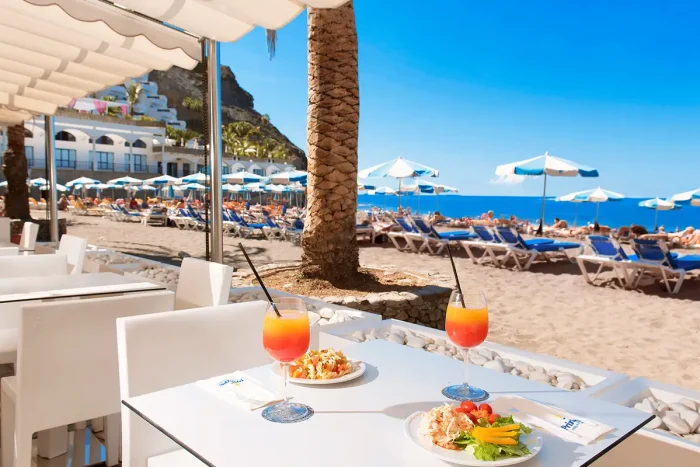 widok na stolik z daniami i drinkami na plaży z parasolami i leżakami