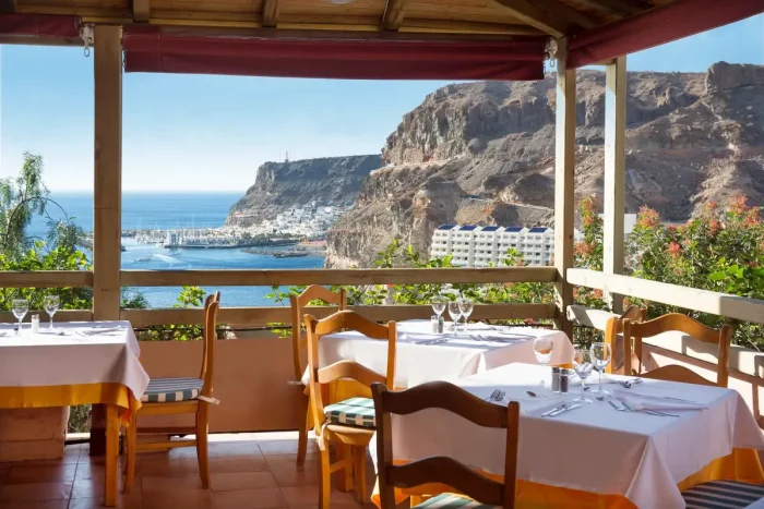 widok z restauracji na stoliki oraz krajobraz gór i ocean