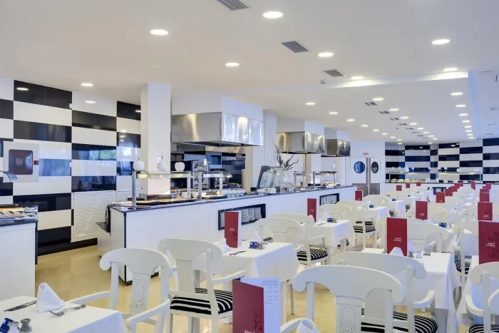 hotelowa restauracja z stolikami krzesłami i miejscem serowania posiłków